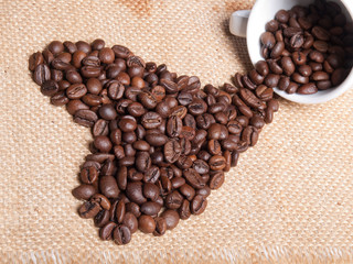 white cup with coffee beans on burlap background. heart symbol.