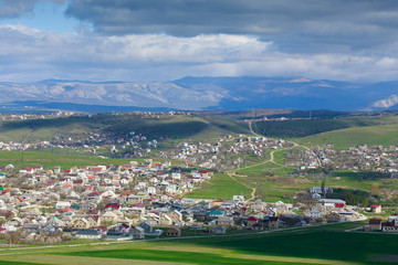 Village valley against the background mountains and cloudy sky