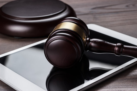 judge gavel and tablet computer on brown wooden backgroundjudge