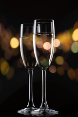 Champagne in glass on black background with color bokeh