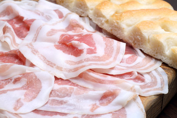 Bacon slices with focaccia on wooden cutting board