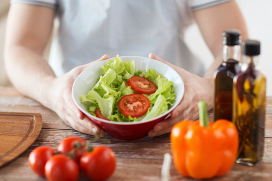 close of male hand holding a bowl with salad