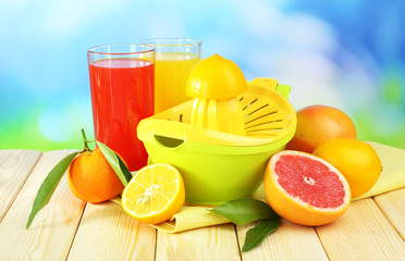Citrus press and fruits on table on blue background