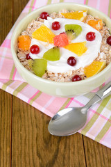 Delicious oatmeal with fruit in bowl on table close-up