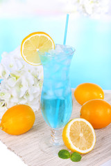 Glass of cocktail on table on light blue background