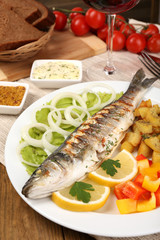 Delicious grilled fish on plate on table close-up