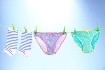 Baby clothes hanging on clothesline, on bright background