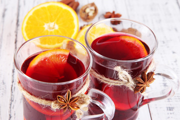 Mulled wine with oranges and spices on wooden background