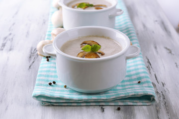 Mushroom soup in white pots, on napkin,  on wooden background