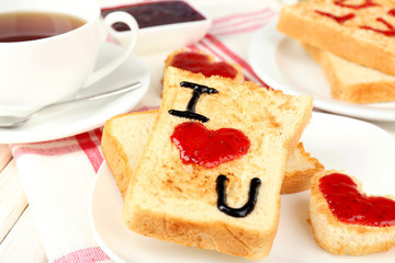 Delicious toast with jam and cup of tea on table close-up