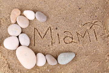 Fototapeta na wymiar Inscription Miami in wet sand close-up background