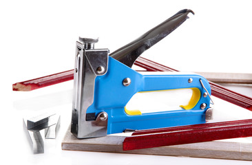Construction stapler and wooden frames isolated on white