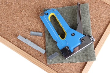 Construction stapler and staples on cork board close up