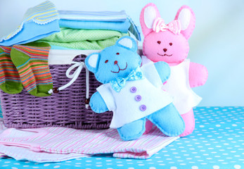 Pile of baby clothes  in basket, on table on color background