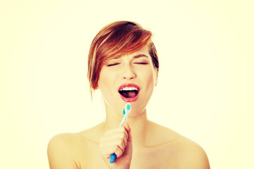 Beautiful young woman singing to tooth brush