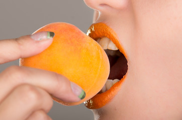 Beautiful young woman eating a peach.
