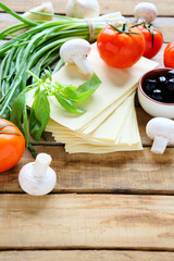 Lasagna and ingredients, mushrooms, tomatoes, greens