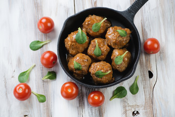 Meatballs with cherry tomatoes and corn salad leaves, above view