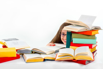 Girl hiding behind stack of colorful books and smiling