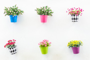 Plastic flower in vase on wall background