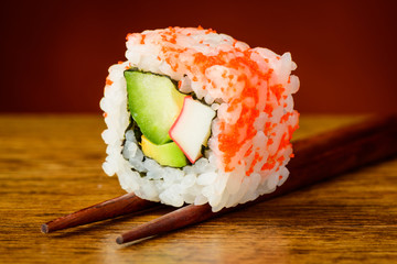 Uramaki sushi closeup on chopsticks