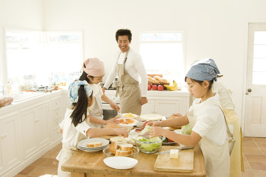 Japanese Father And Four Daughters Cooking In Kitchen