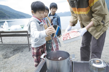 adult male and three boys making curry by lakeside - Powered by Adobe