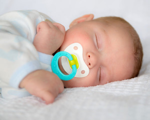 Infant baby boy sleeping peacefully with pacifier
