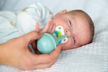 Mother using bulb syringe to clean baby's nose