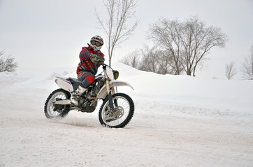 Motocross on snow, the driver manages motorcycle one arm on snow