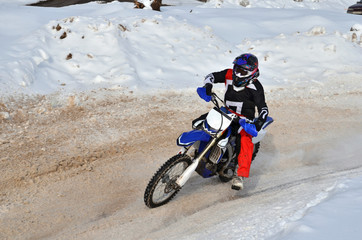 Motocross on snow racer on a motorcycle in the left turn having