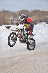 Motocross rider on a motorcycle driving on winter road holding u