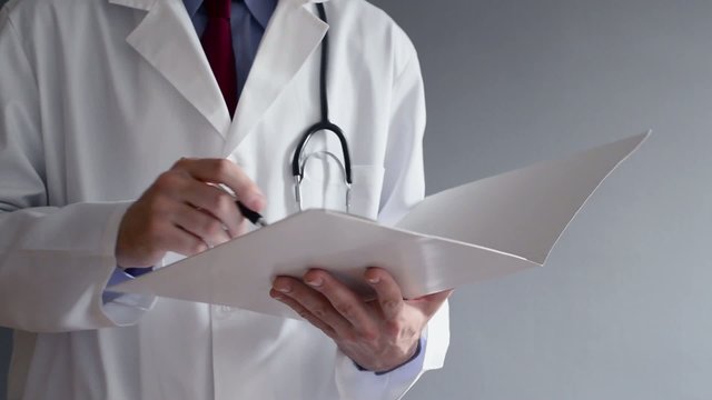 Male doctor writing prescription while standing.