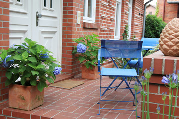 Backsteinhaus mit blauen Gartenmöbeln und Hortensien