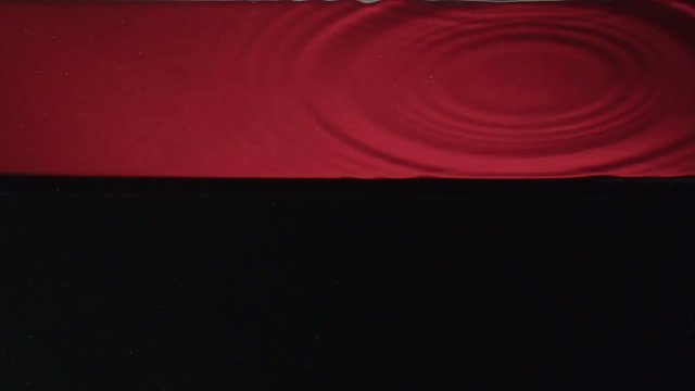 drop falling into water over red-black backround in slowmotion