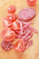 Sausage and tomatoes on a cutting board.