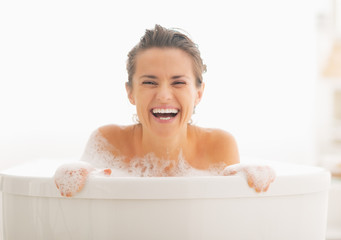 Smiling young woman looking out from bathtub
