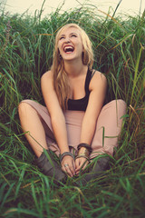 Girl sitting in the grass and laughing.Laughing girl.Enjoyment.T