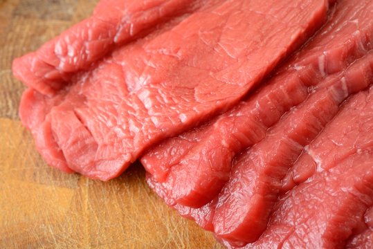 Fettine di carne di manzo crude sul tagliere di legno