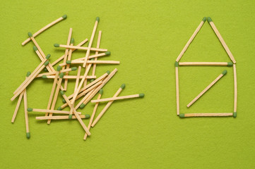 Little house made of matchsticks on green felt