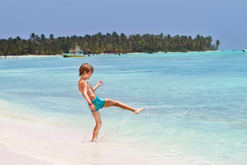 Fototapeta na wymiar Little boy playing in the ocean on a tropical beach