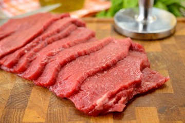 Fettine di carne di manzo crude sul tagliere di legno