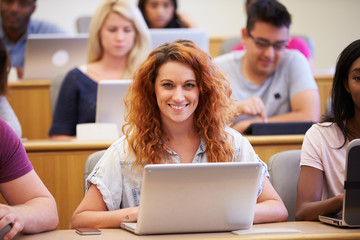 Fototapeta na wymiar Female University Student Using Laptop In Lecture