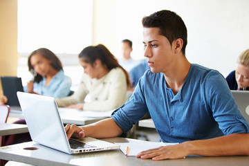 Male High School Student Using Laptop In Class