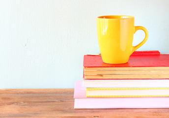 yellow cup of coffe on old vintage books