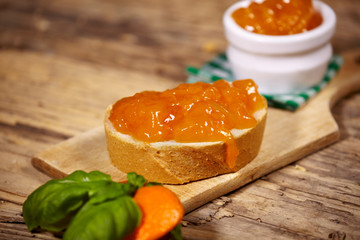 orange jam with slice of bread on wooden table