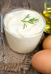Mayonnaise in bowl with egg and olive oil on an old wooden table