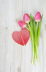 three pink tulips tied with a ribbon and valentine candy