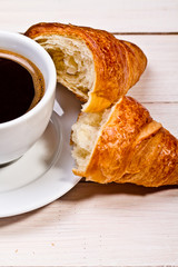 Coffee cup with a croissant isolated on wooden table 