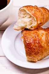 Coffee cup with a croissant isolated on wooden table 